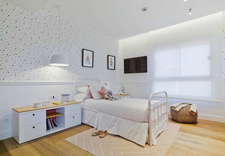Habitación infantil con friso de madera y papel pintado de topos