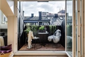 Terraza urbana pequeña contigua a salón con mesa y sillas de hierro negro